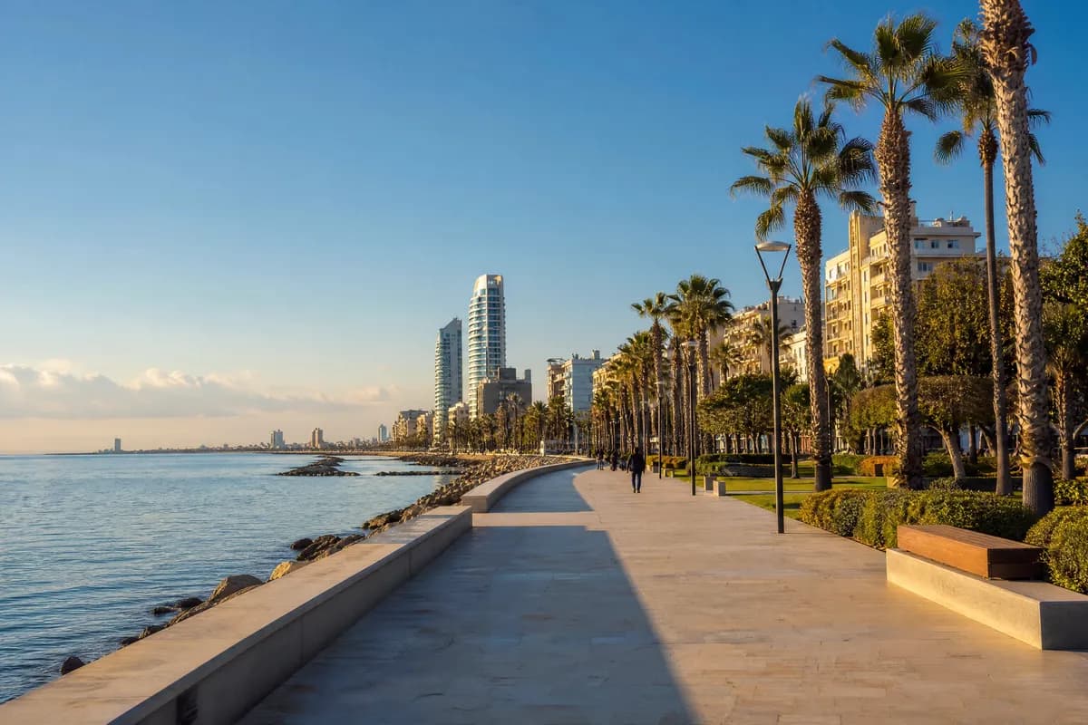 Seafront promenade with palm trees, a calm sea and apartment towers along the bay. Illustrative image, not a photograph of a specific place.