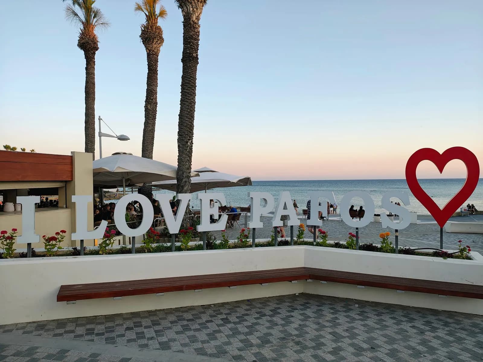 Promenada w Pafos ze znakiem I love Paphos, palmami i plażą nad Morzem Śródziemnym o zmierzchu